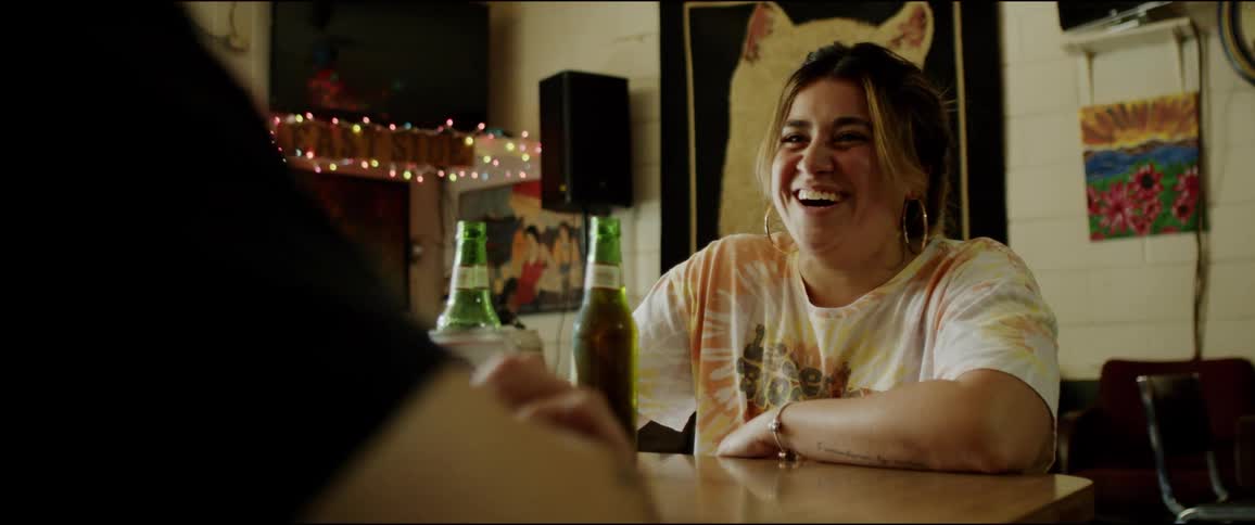 Friends sit at table with bottled drinks talking and laughing