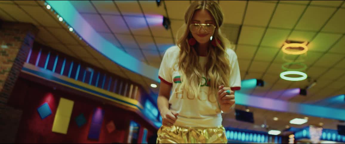 A woman dances as she skates under neon lights a roller rink