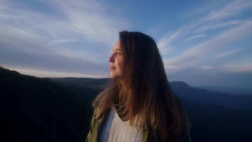 Young woman looking at the sun on the peak of a mountain at morning