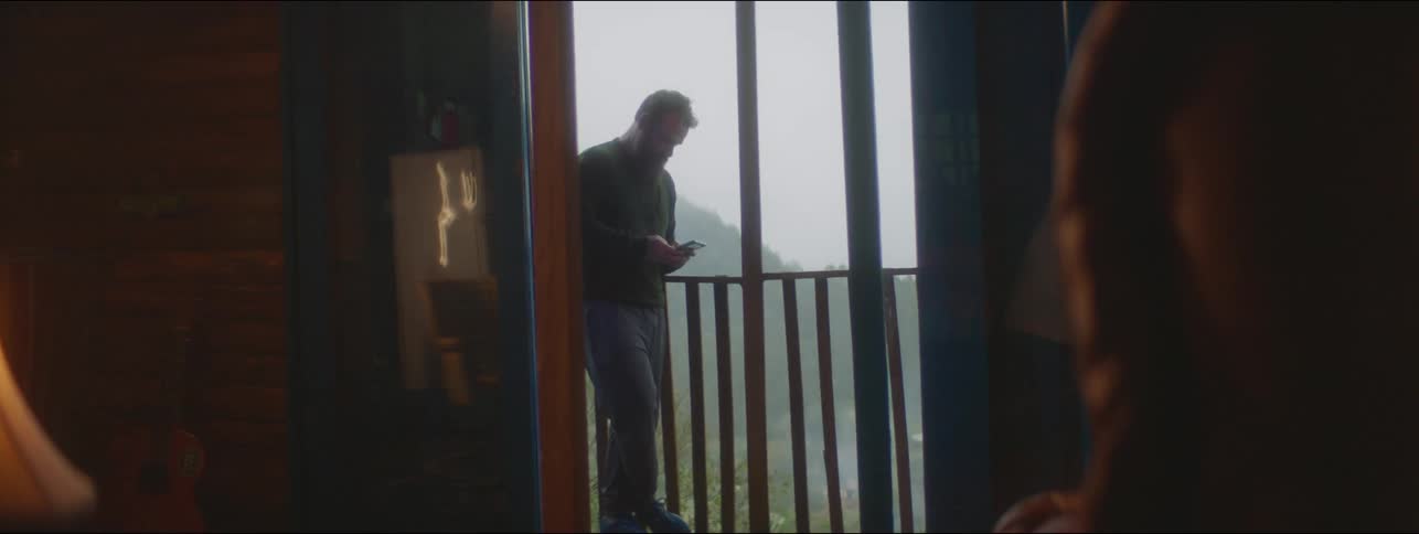 A man is looking at his cell phone on the terrace