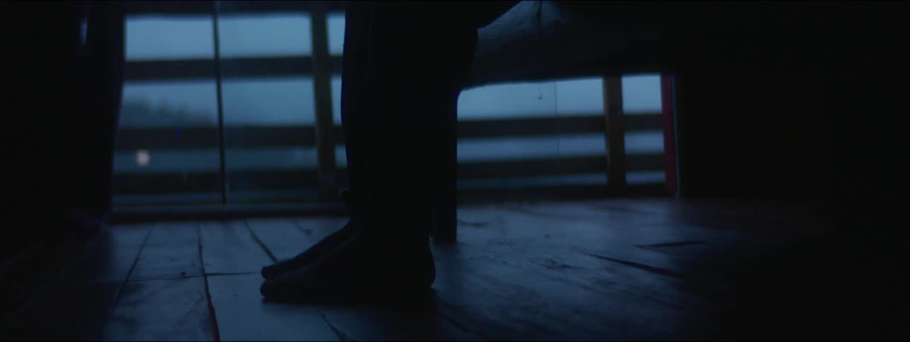 A person standing from a couch inside a dimly lit room