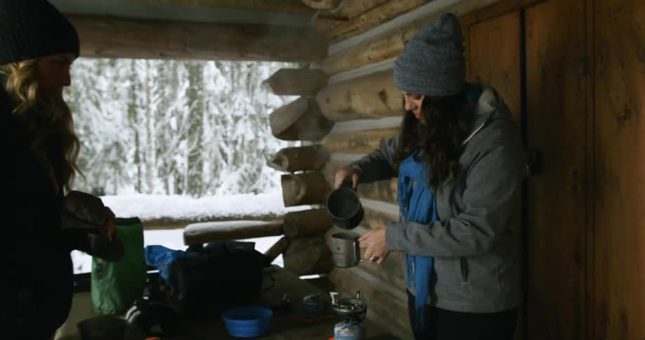 A dark haired woman pours a steaming cup