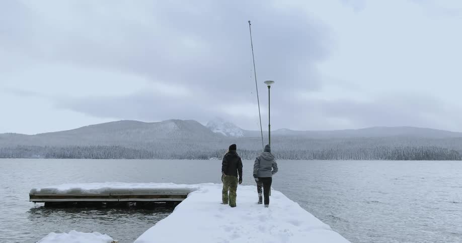 Two people walk down a snow covered pier