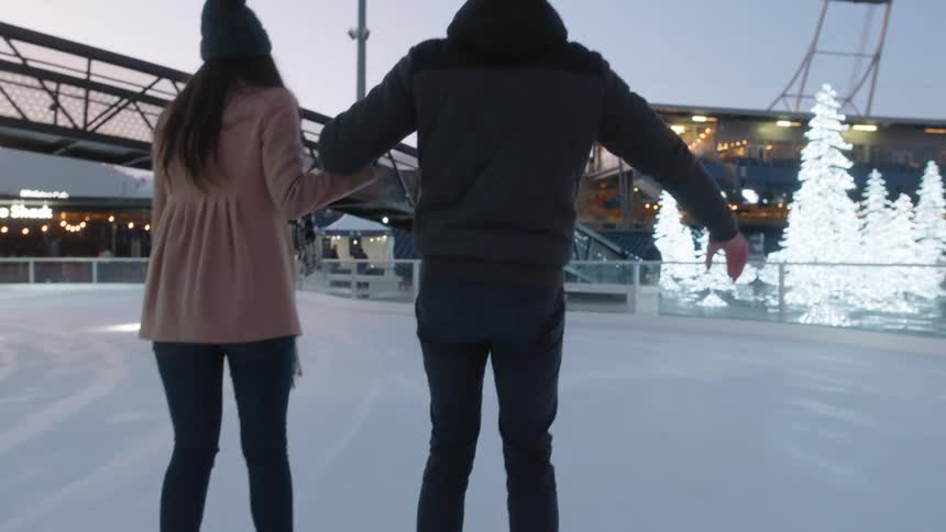 Couple play ice skating at evening