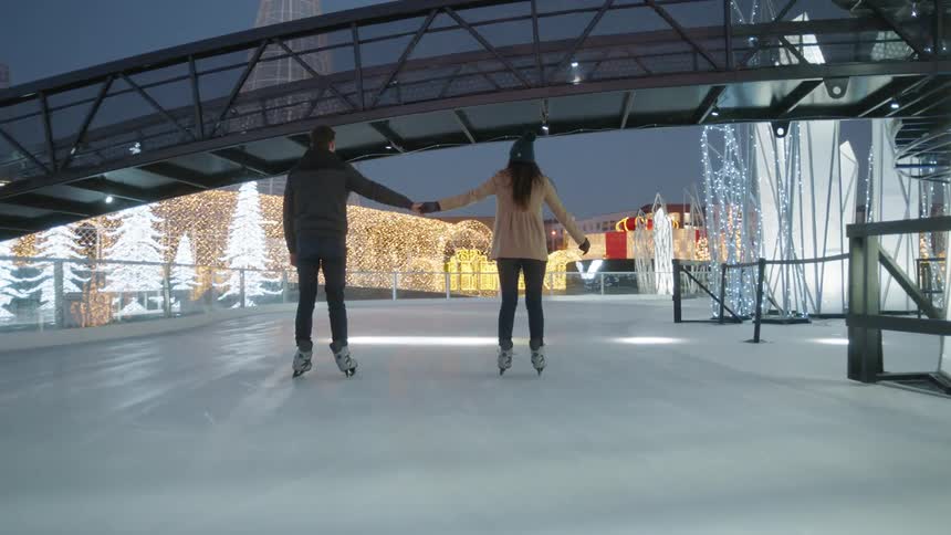 Two people are ice skating together at dawn