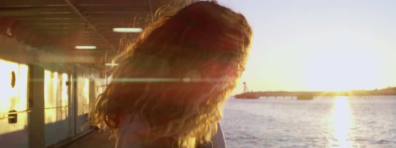 A woman looks out at the water at sunrise