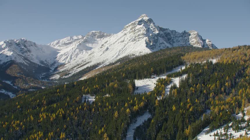Snow covers mountain and forest covered slopes