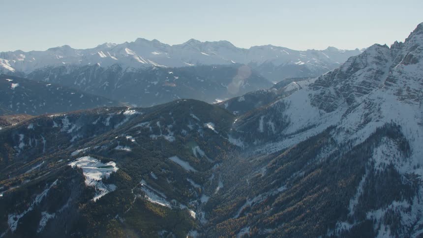Pockets of snow fall between trees on the side of a mountain