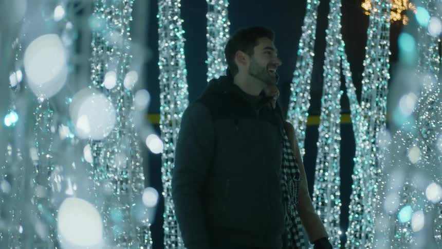 A couple walks through christmas lights