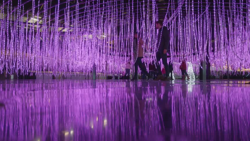 A couple walk through a hanging light string display