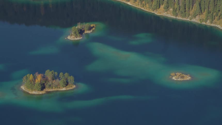 Tall trees cover a set of islands in a clear blue sea
