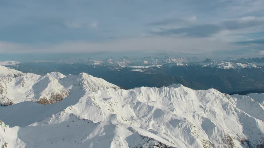 Snow capped mountains covered with forest stretch to horizon on foggy day