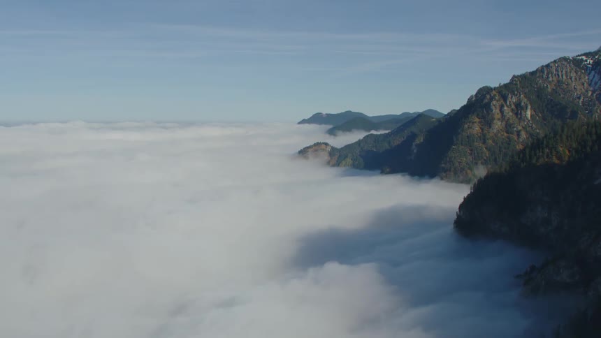 Aerial view of white clouds covering the slopes of a mountain range