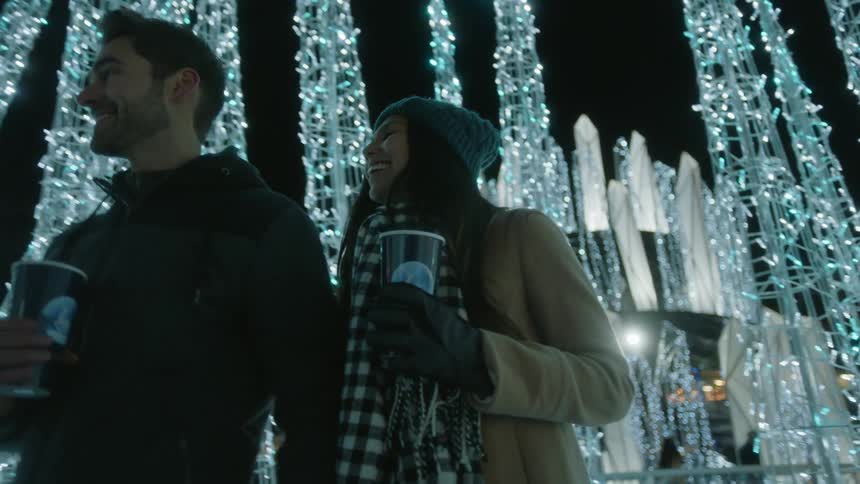 Couple walking through trees of lights