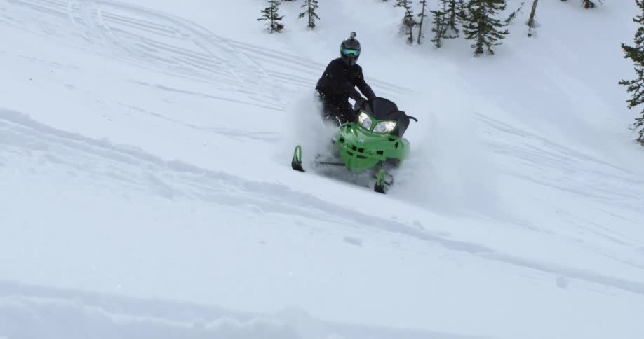 Man riding on side of snowmobile in the snow