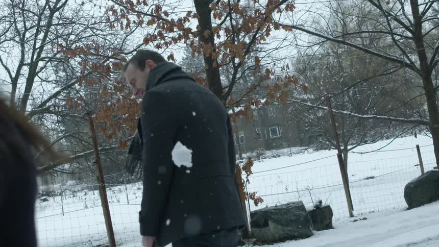A man laughs as he is hit with a snowball