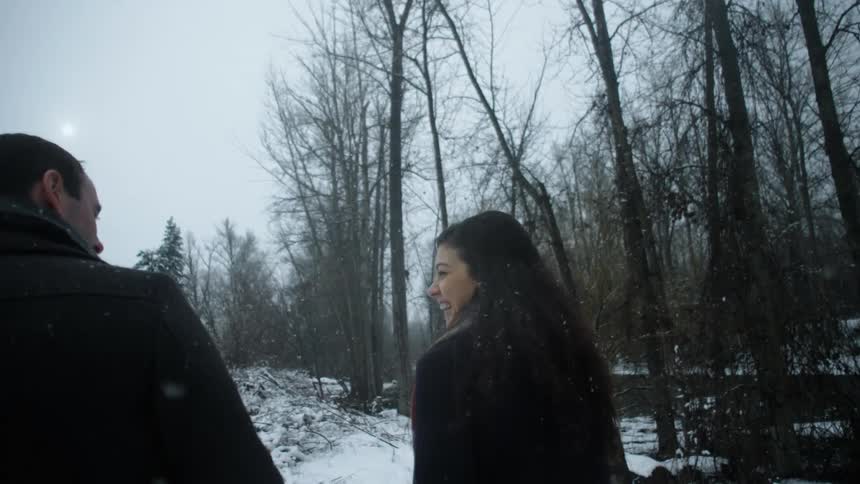 Man and woman walking and laughing while snow falls