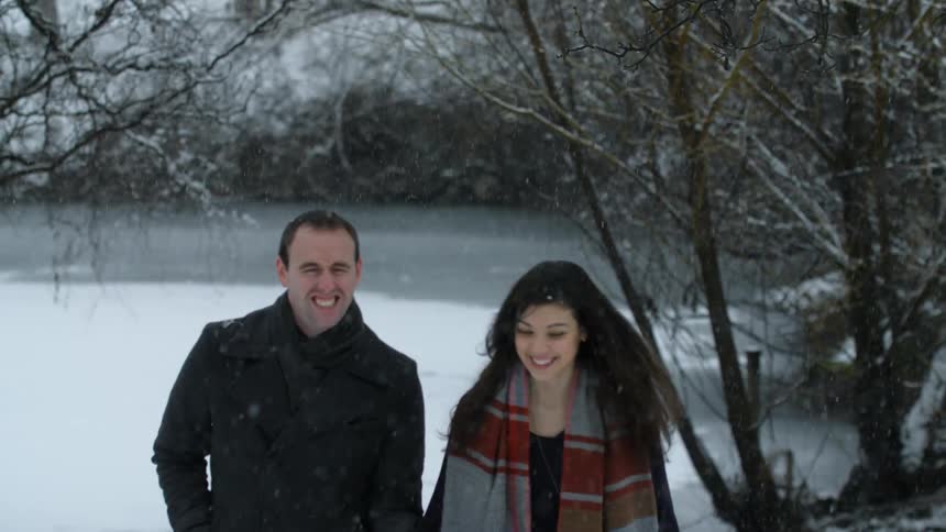 A man and women are walking outside in the snow