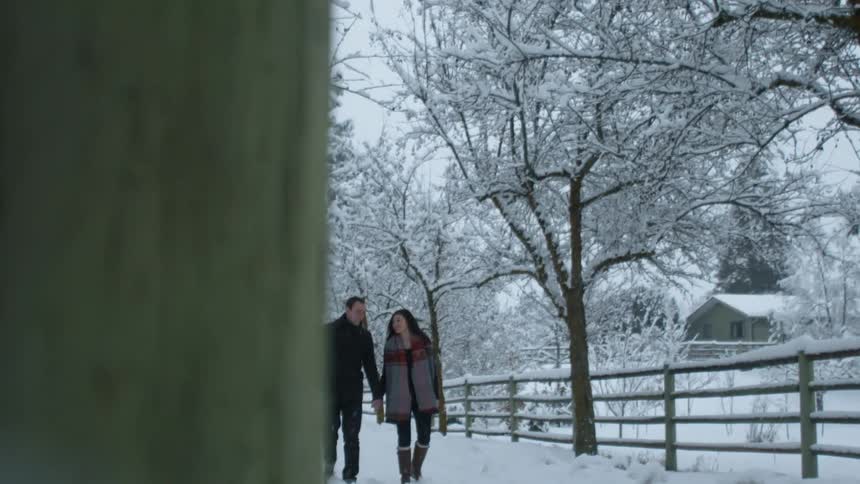 A man and women are holding hands as they walk in the snow
