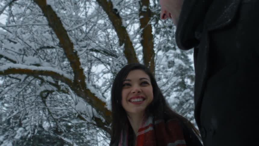 A man and women are talking and walking as it snows