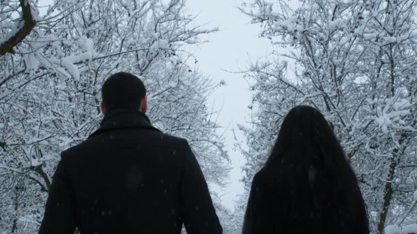 A man and women walk outside as it snows