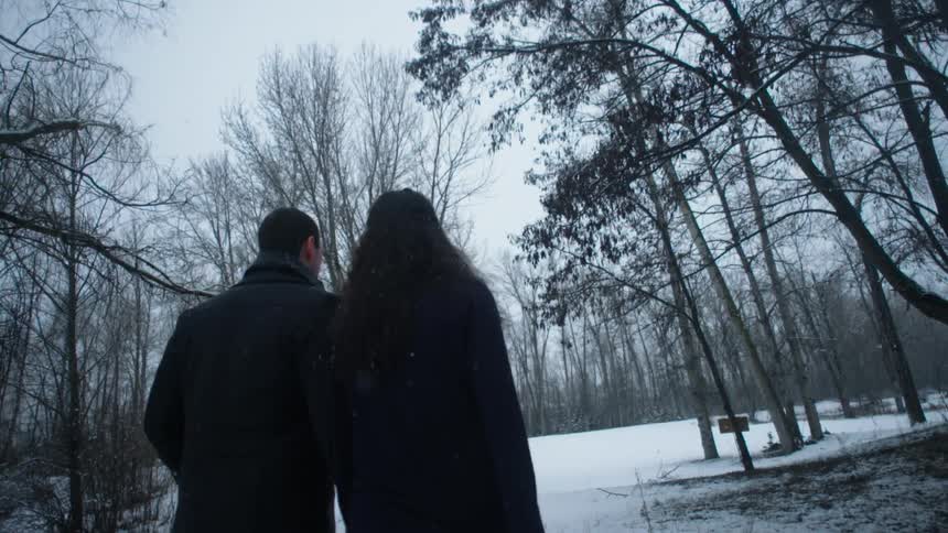 A man and woman walk hand in hand on a snowy day