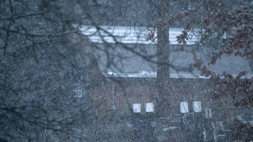 Heavy snowfall in front of a barn