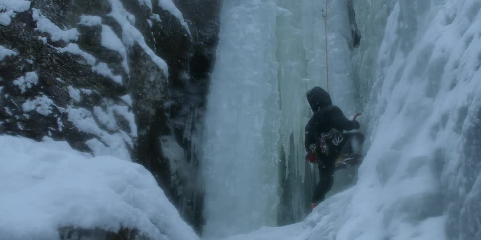 Snow falls on a rock climber