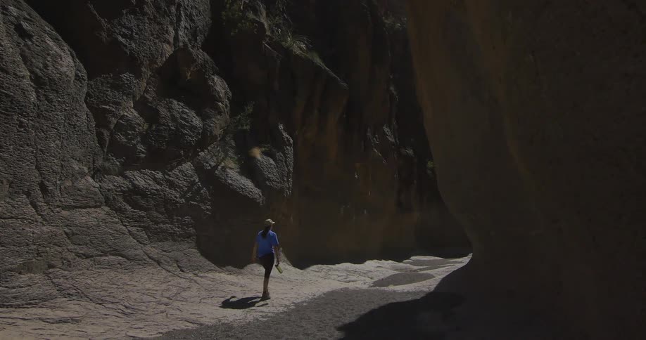 A woman walking along a path through steep cliffs