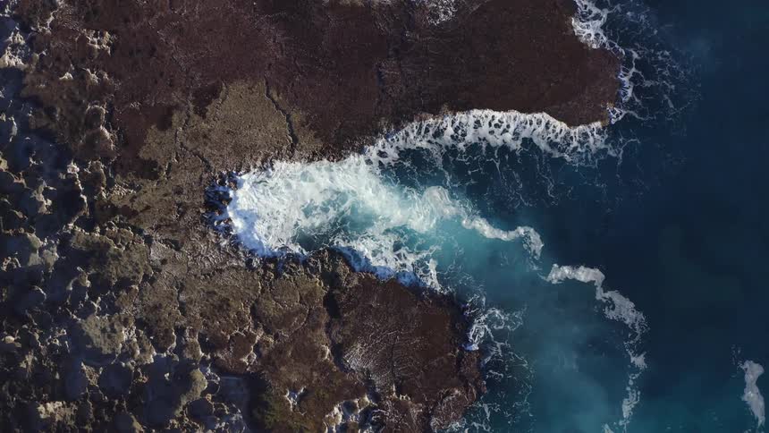 Waves crash against shore creating foam