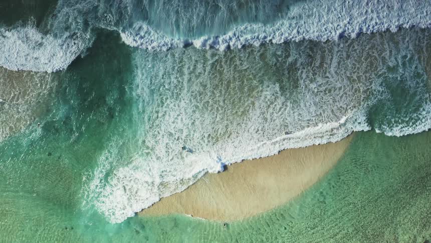 The waves flood over the small patch of sand