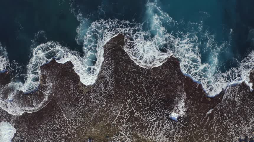 A birds eye view of waves crashing in to the shore