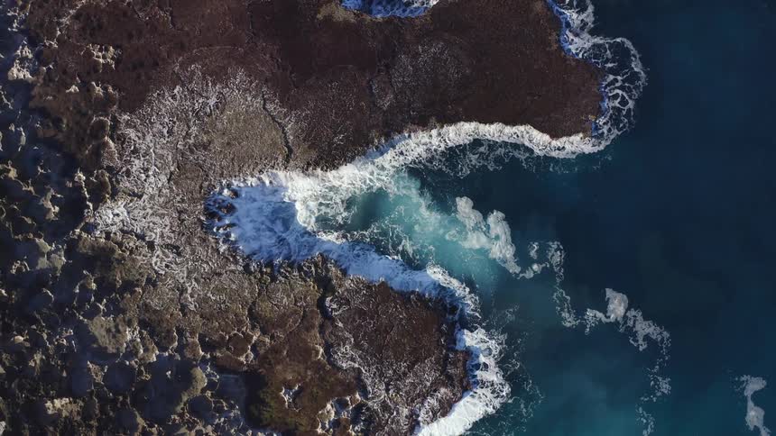 Waves wash upon the shore below cliffs