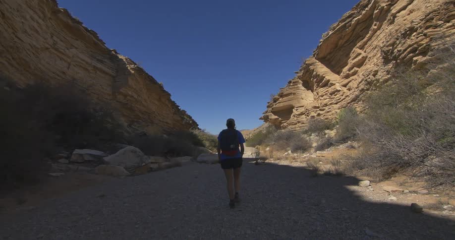 A woman hiking on a dirt path between cliffs