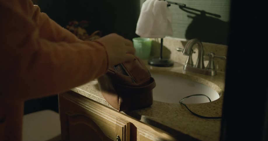A person stores all personal belongings on a small pouch over the bathroom sink