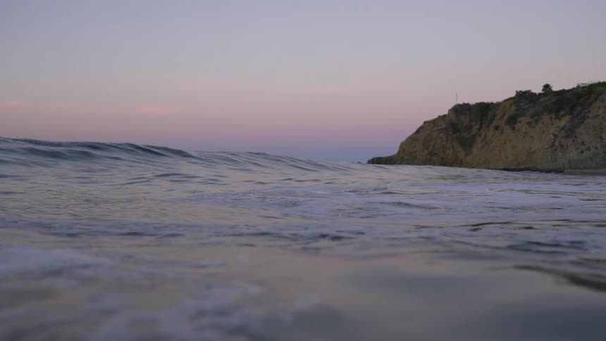 Ocean waves wash onto the beach at sunrise
