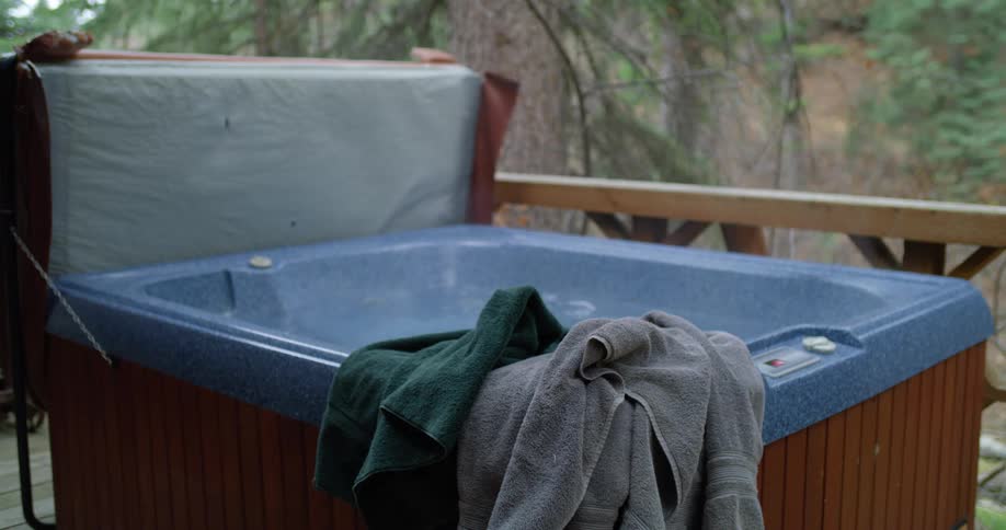 A hot tub jacuzzi is on a deck and the water inside is bubbling and steaming