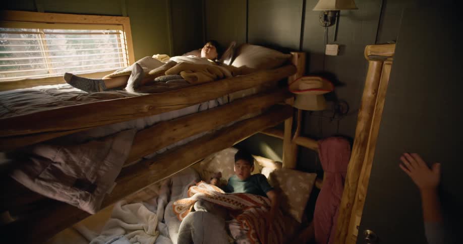 Mother opens door and wakes children sleeping on bunk beds with rustic log framework