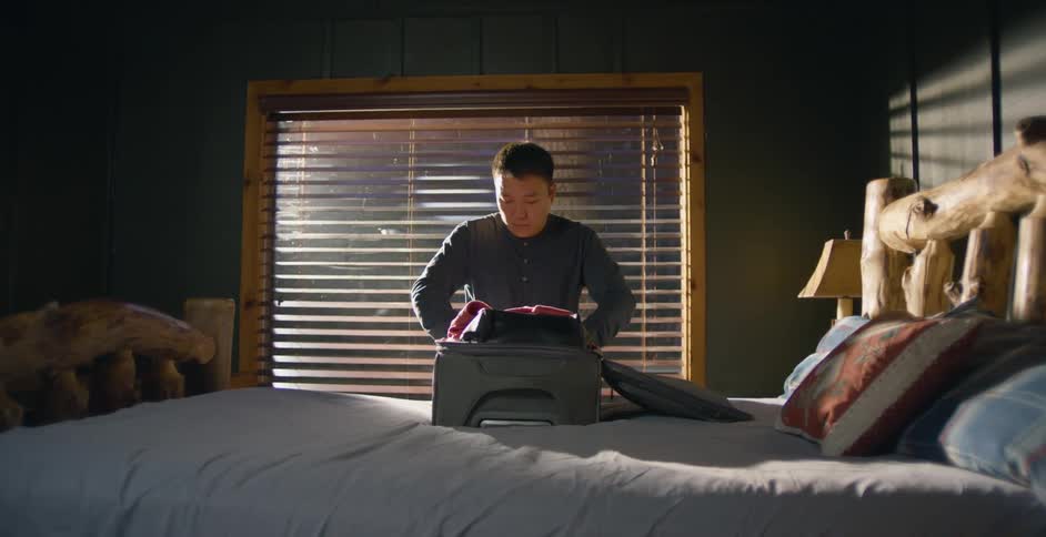 A man packing a suitcase on a bed