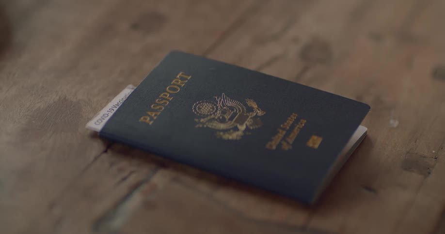 A passport is sitting on a table and someone takes it