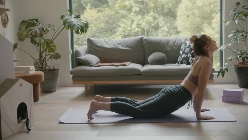 Woman with sports bra black pants works out on mat in living room at home