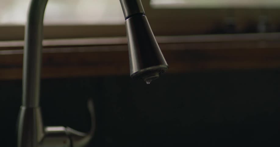Water drops from a kitchen faucet inside a home
