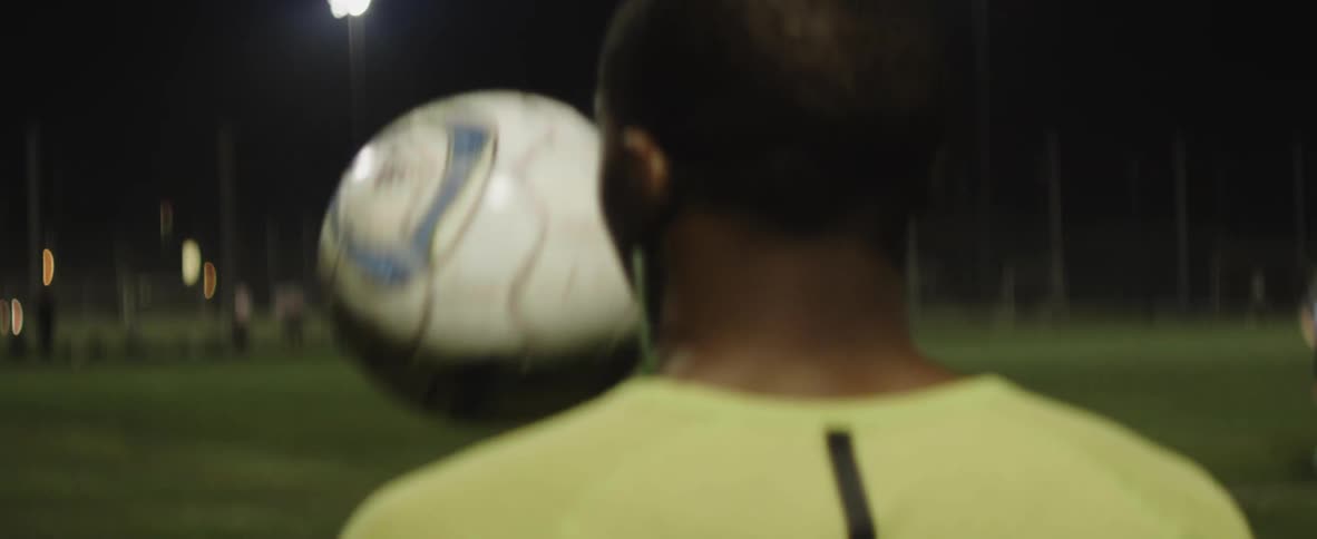A man throws a soccer ball up and down on the field