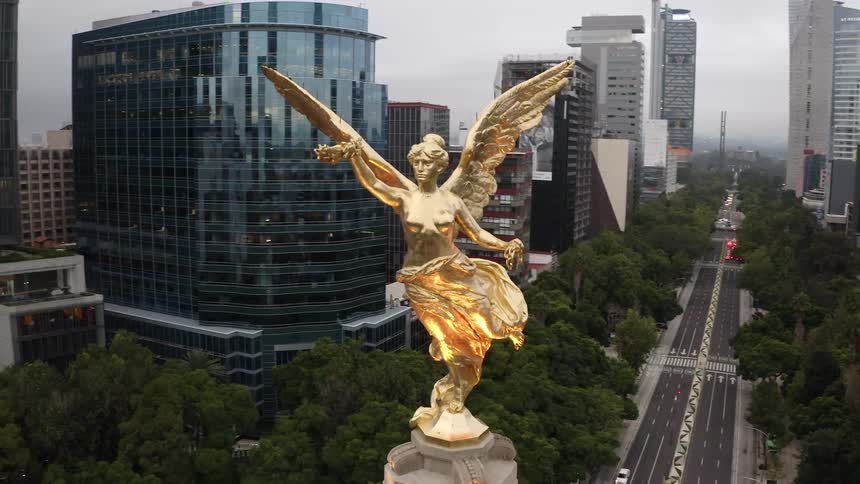 A gold statue with angel wings sits surrounded by skyscrapers downtown