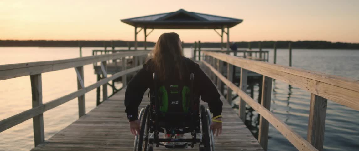 A woman in a wheelchair out on a pier