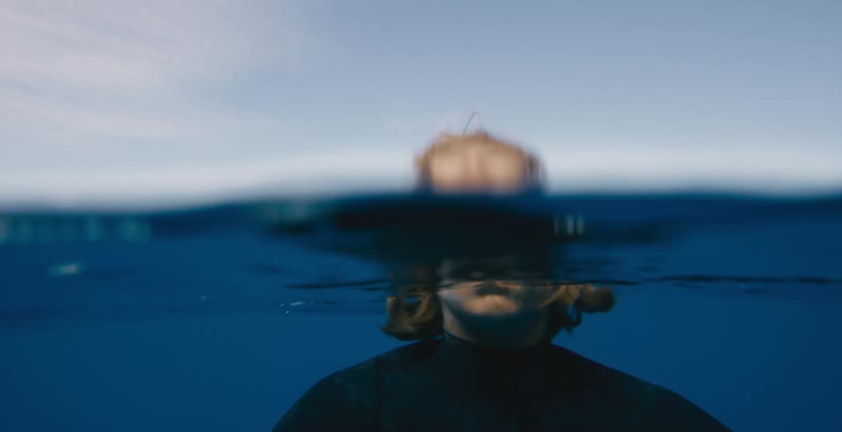 Underwater view of a man in the water and it moves to the surface with his head above water