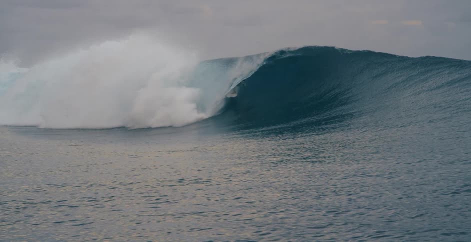 A man is surfing on a large wave
