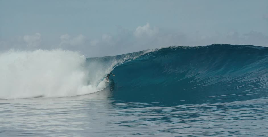 A surfer is riding a big wave as the water splashes overhead he stays on the surfboard