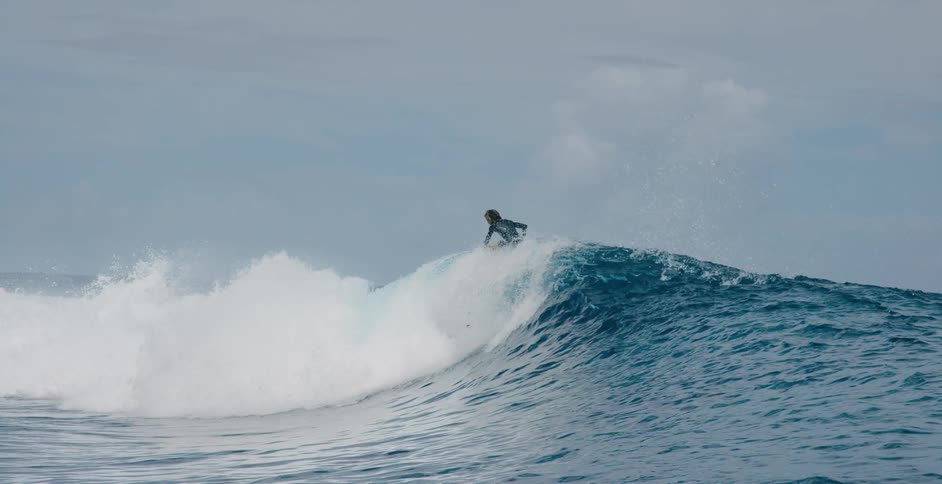 A surfer rides a curling breaking wave