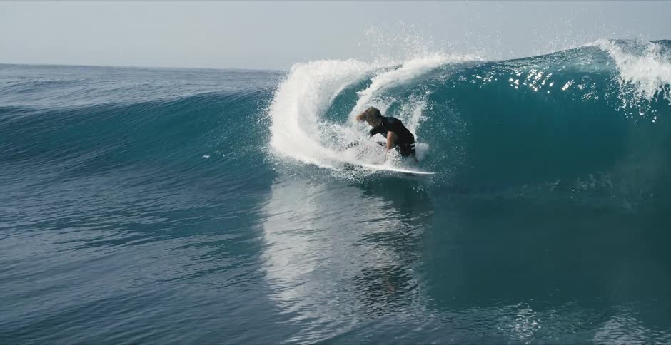A surfer rides a wave as it curls and breaks and splashes